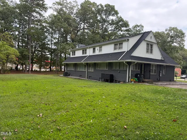 a view of a house with a yard and large trees