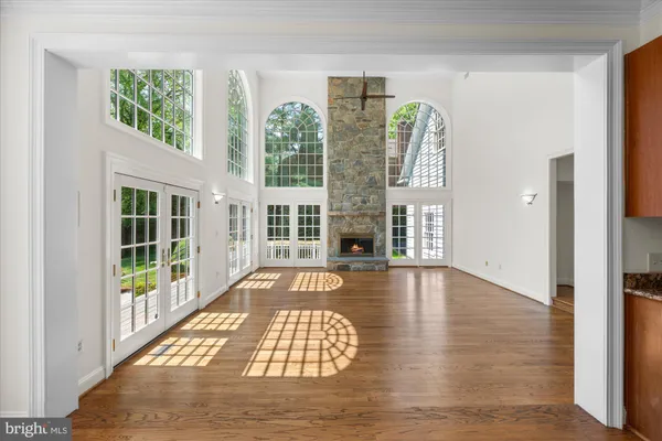 a view of an empty room with wooden floor and windows