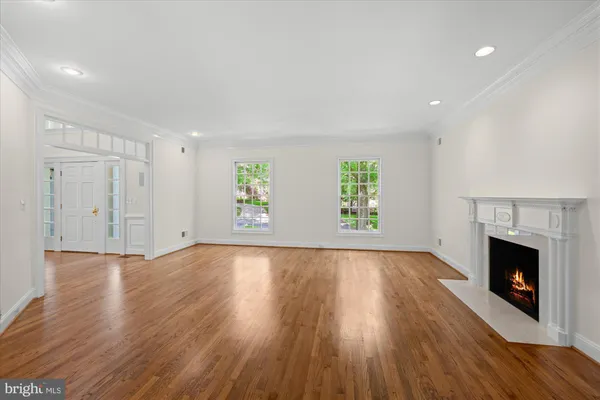an empty room with wooden floor fireplace and windows
