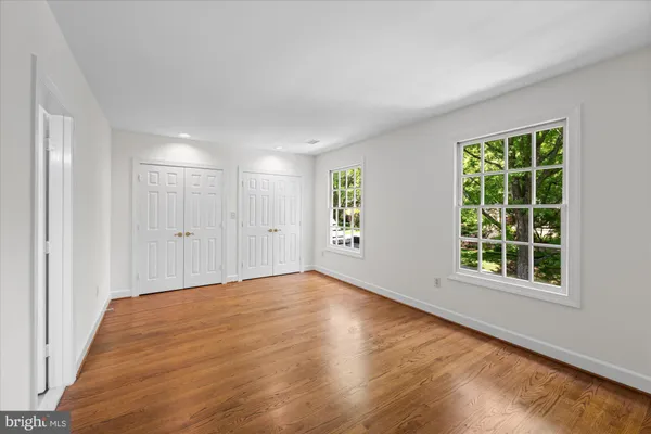 a view of an empty room with wooden floor and windows