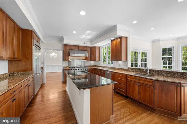 a kitchen with stainless steel appliances granite countertop wooden cabinets a sink dishwasher a stove and a refrigerator