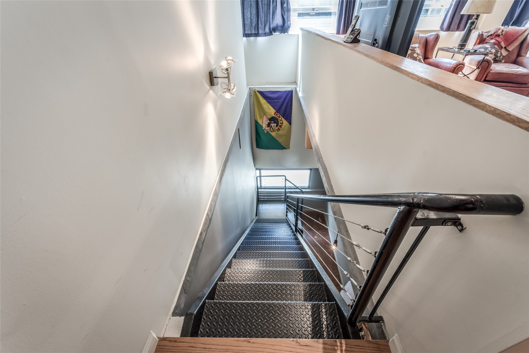 705 Main Street, Unit 215 Houston, TX 77002 - Photo 19 of 36 This photo showcases a modern staircase with metal steps and a sleek railing, leading to lower level area to primary bedroom with natural light from large windows.