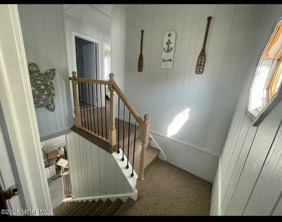 a view of staircase with lots of frames on wall and a window