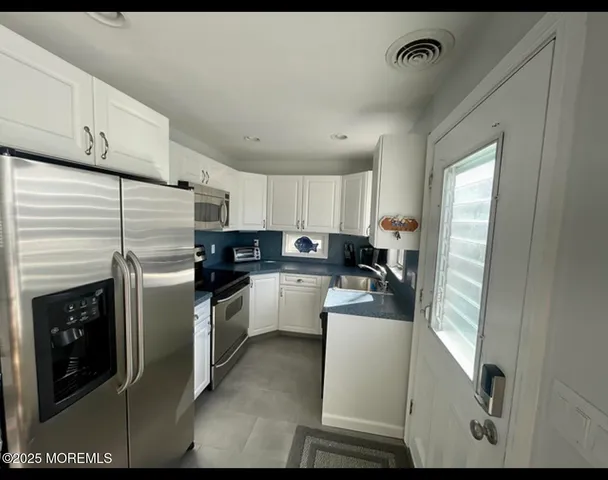 a kitchen with a refrigerator sink and cabinets