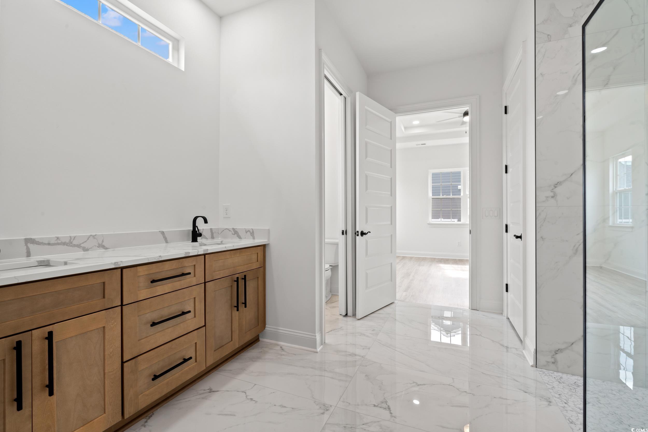 1009 Englemann Oak Drive Myrtle Beach, SC 29579 - Photo 19 of 38 Bathroom with plenty of natural light, light marble finish floors, a marble finish shower, and double vanity