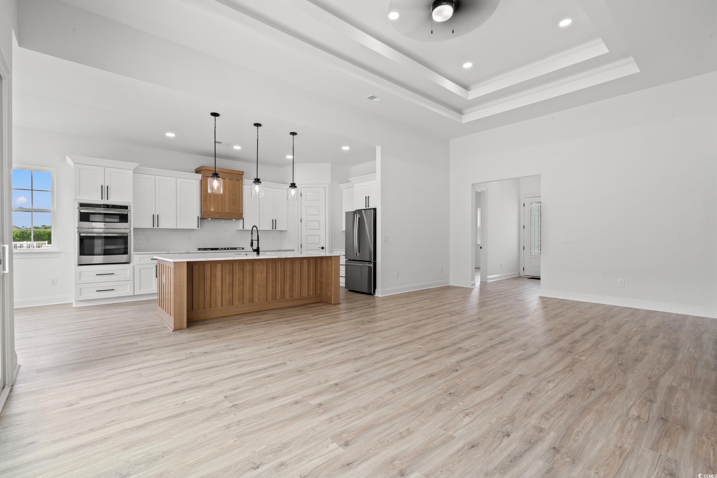 1009 Englemann Oak Drive Myrtle Beach, SC 29579 - Photo 38 of 38 Kitchen with light countertops, open floor plan, brown cabinetry, pendant lighting, and light wood-style floors