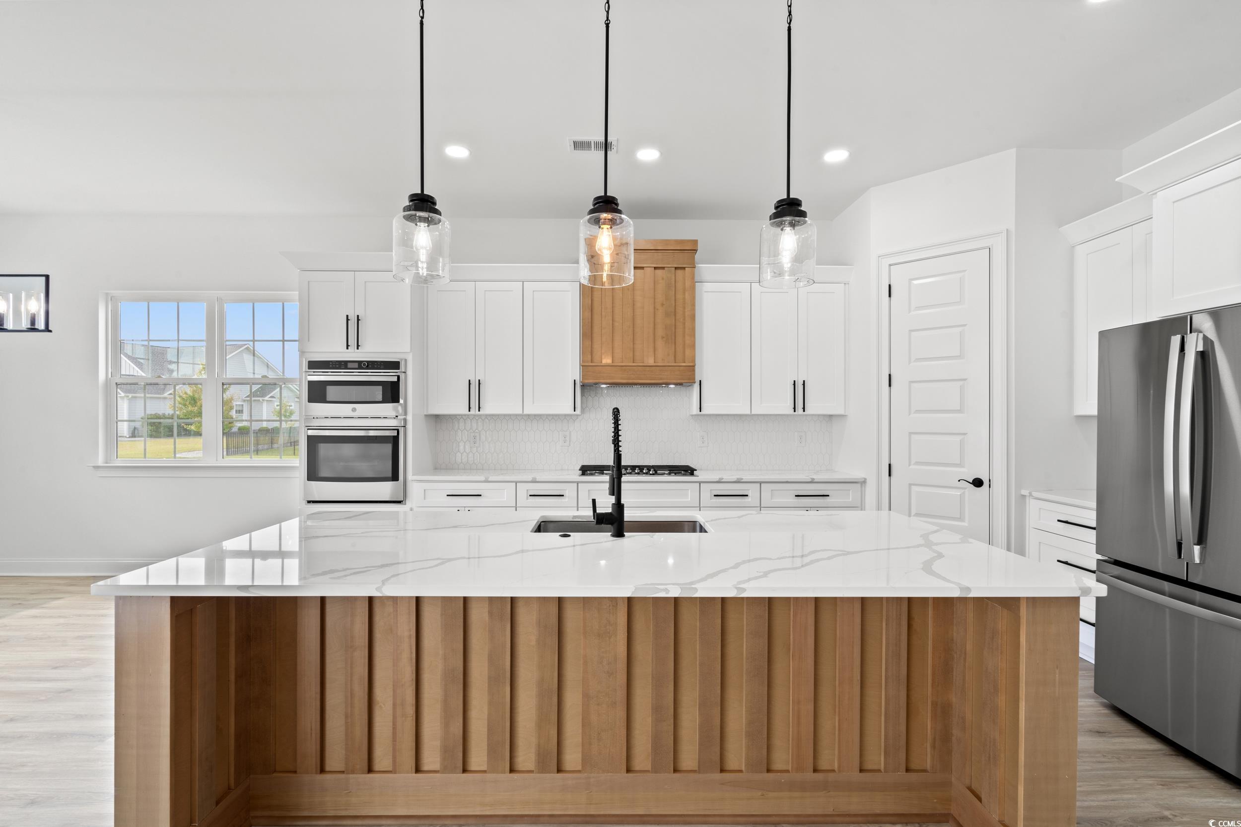1009 Englemann Oak Drive Myrtle Beach, SC 29579 - Photo 7 of 38 Kitchen with light wood-type flooring, decorative backsplash, light stone counters, stainless steel appliances, and recessed lighting