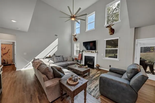 a living room with couches a fireplace and kitchen view with wooden floor
