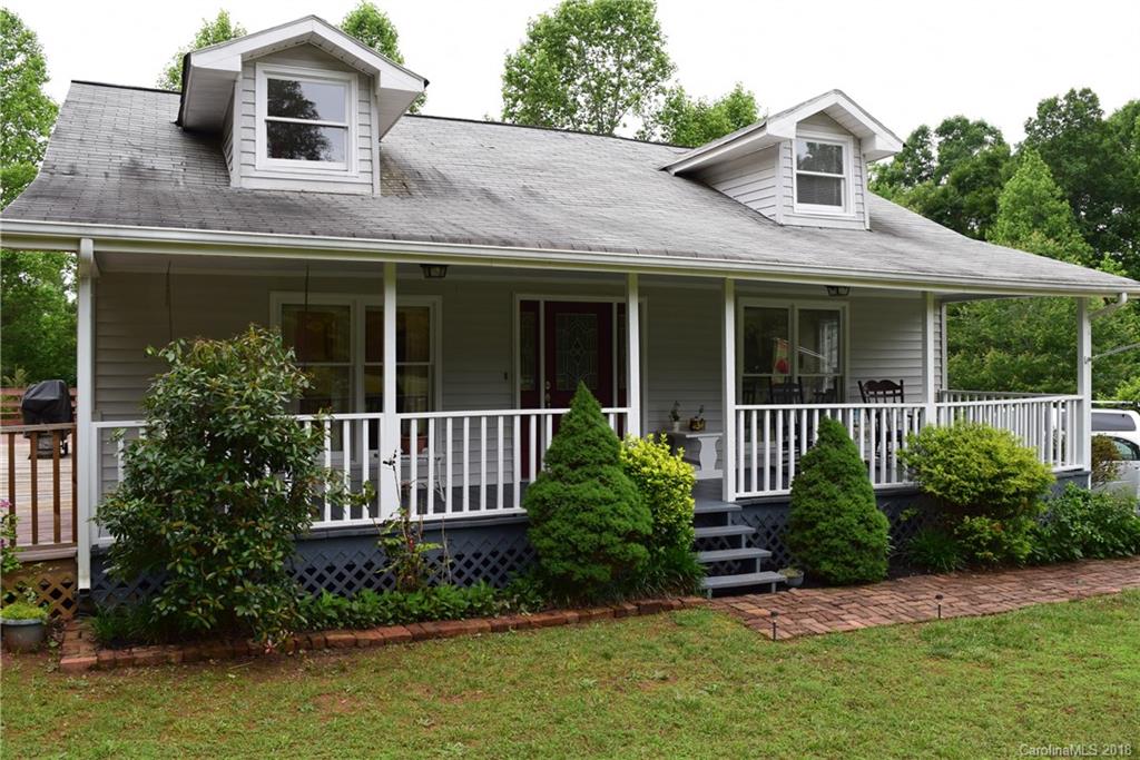a view of a brick house with a small yard plants and large trees