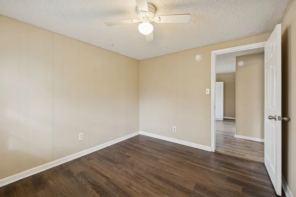 an empty room with wooden floor and a ceiling fan