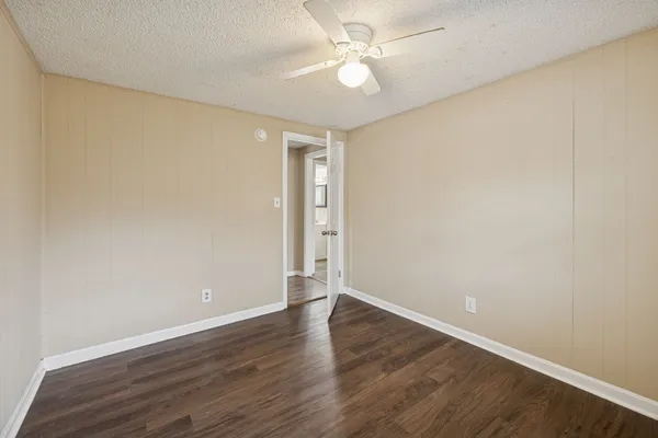 an empty room with wooden floor and fan