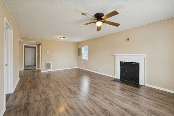 an empty room with wooden floor chandelier and windows