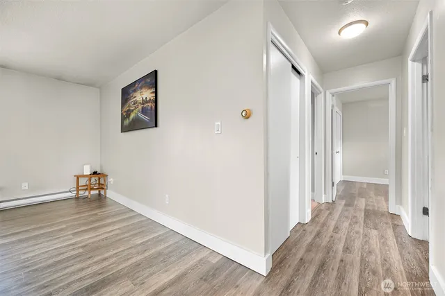a view of a hallway with wooden floor and a bathroom