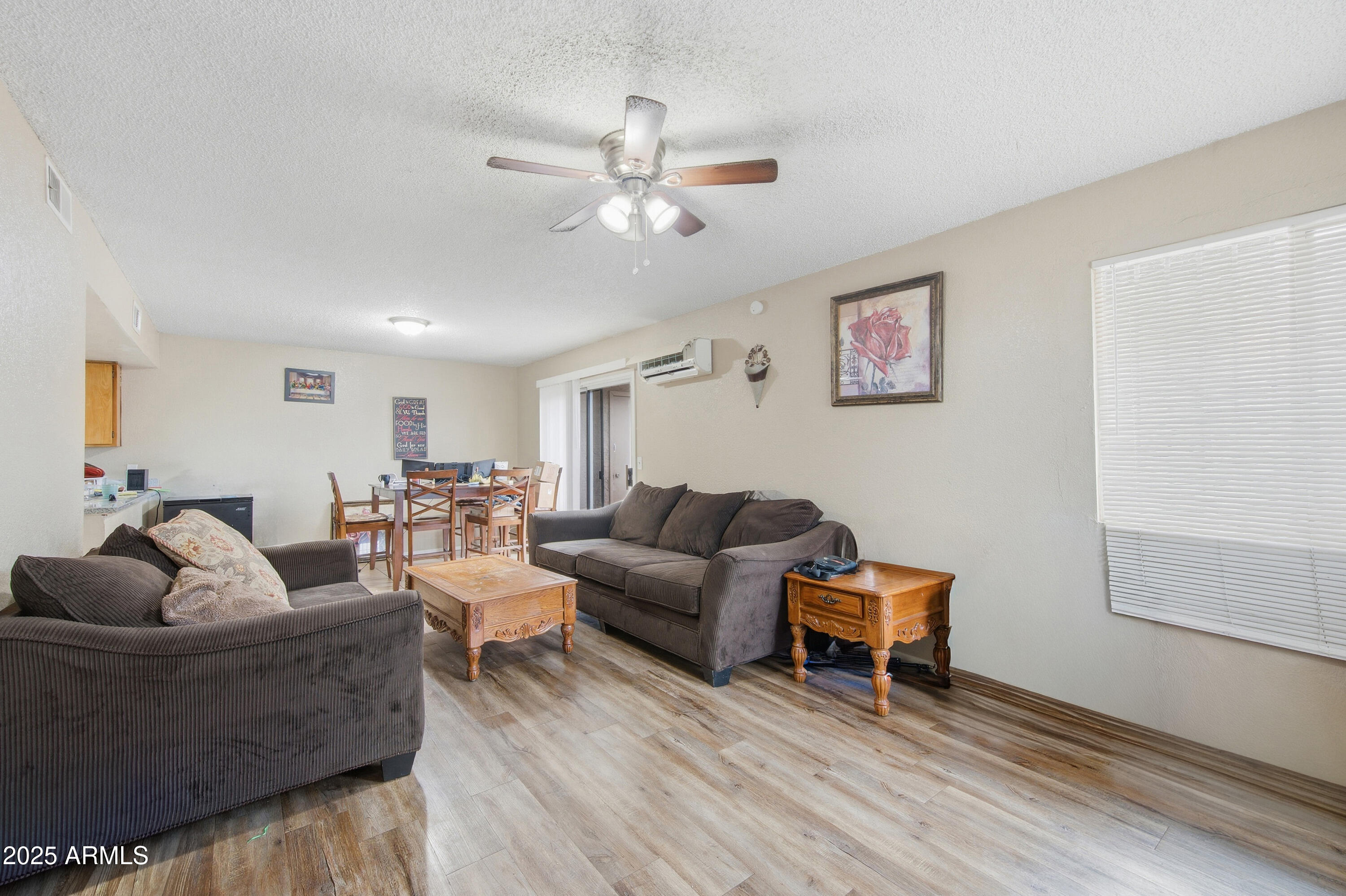 4242 North 69th Lane, Unit 1333 Phoenix, AZ 85033 - Photo 4 of 18 a living room with couches and a potted plant on a dresser with wooden floor