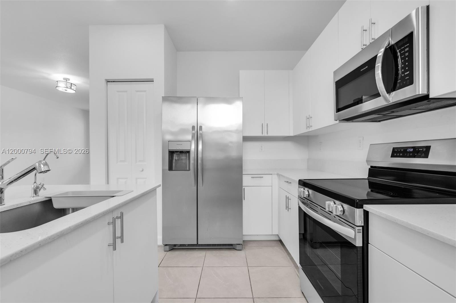 23077 Southwest 129th Place Miami, FL 33177 - Photo 10 of 43 a kitchen with stainless steel appliances granite countertop a refrigerator a stove a sink and white cabinets