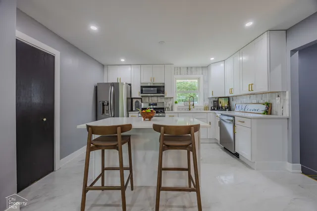 a kitchen with refrigerator a sink and chairs