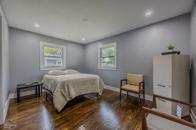 a spacious bedroom with a bed a desk and chair with wooden floor