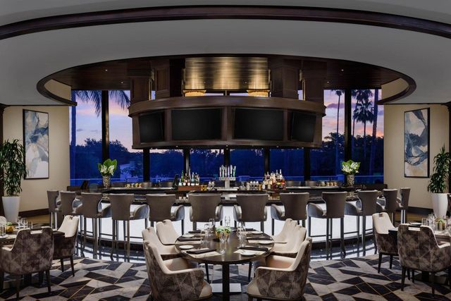 a view of a patio with couches table and chairs under an umbrella with palm trees