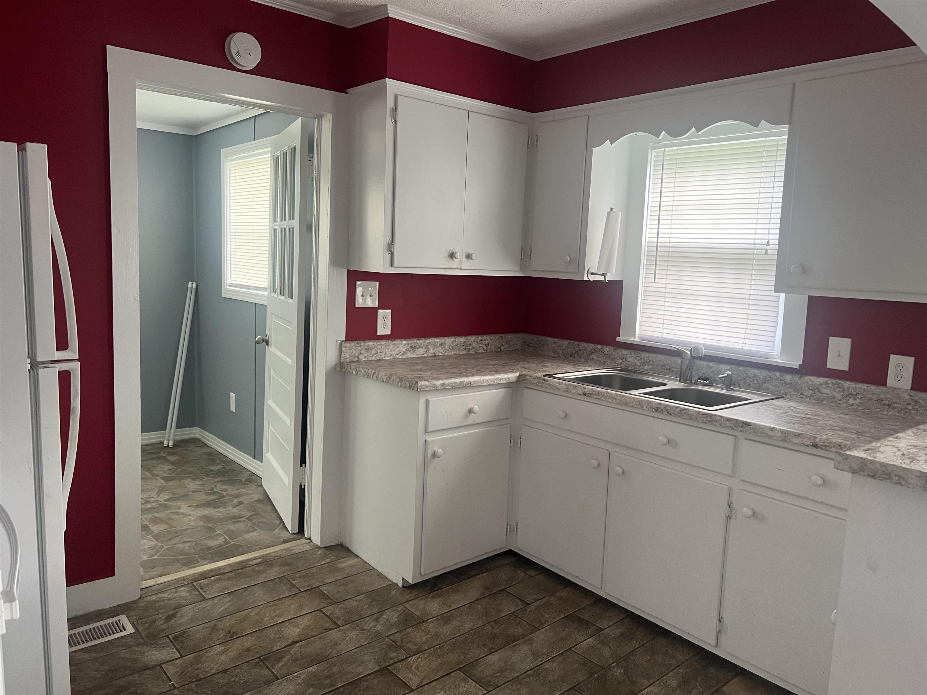 255 North Maple Street Adamsville, TN 38310 - Photo 7 of 17 Kitchen featuring white refrigerator, dark tile floors, crown molding, white cabinetry, and sink