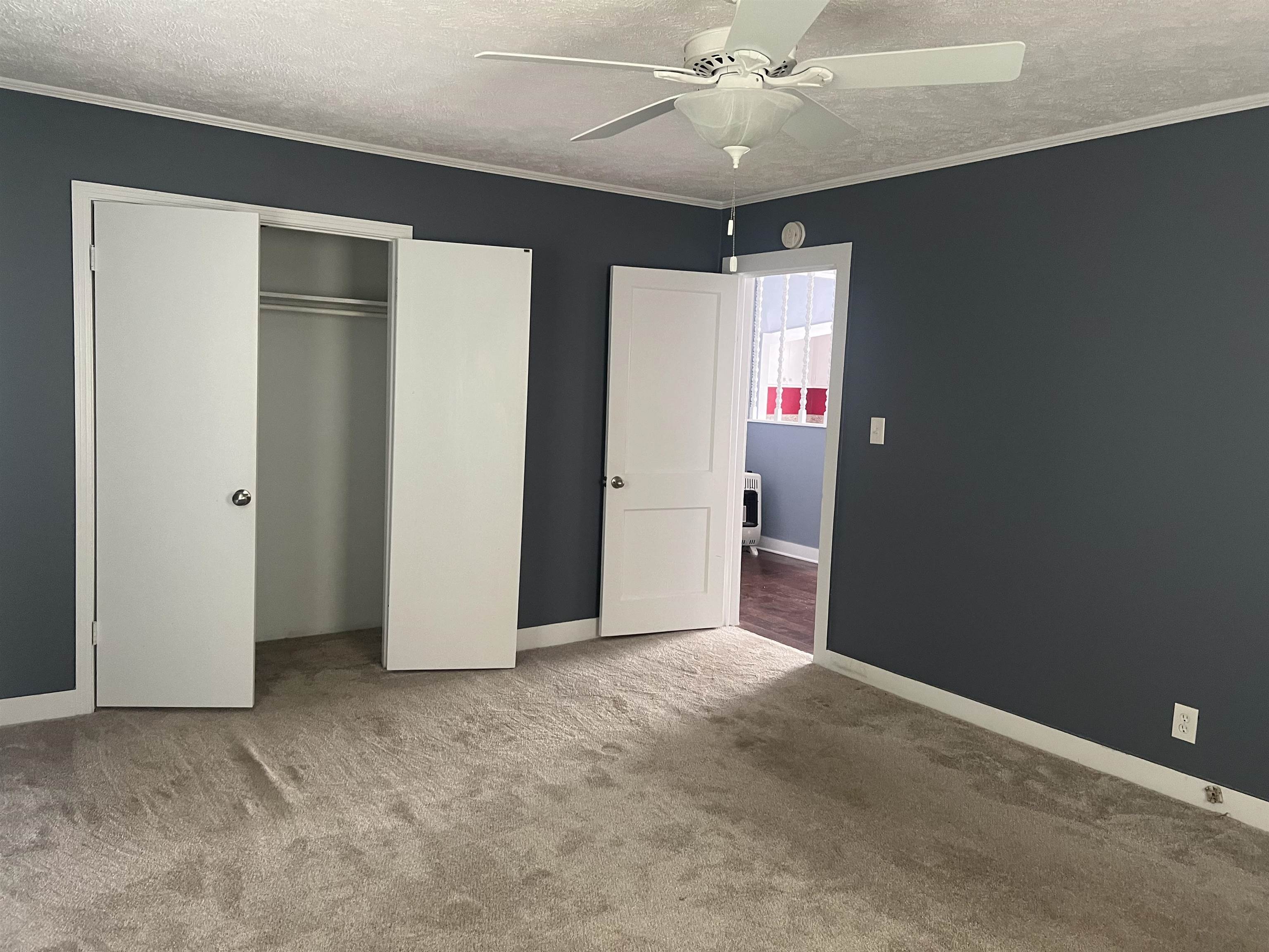 255 North Maple Street Adamsville, TN 38310 - Photo 9 of 17 Unfurnished bedroom featuring carpet, a closet, ceiling fan, ornamental molding, and a textured ceiling