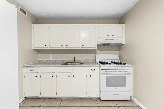 a kitchen with granite countertop white cabinets and white stove