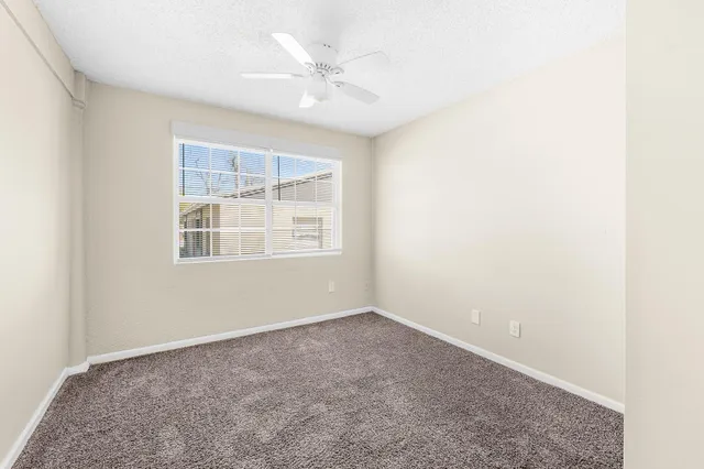 an empty room with windows and fan