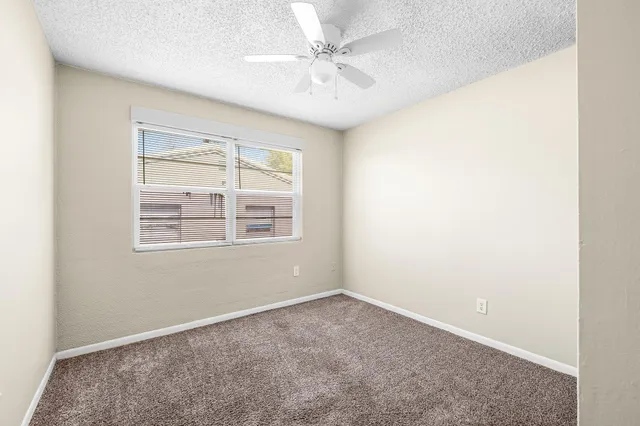 an empty room with windows and fan