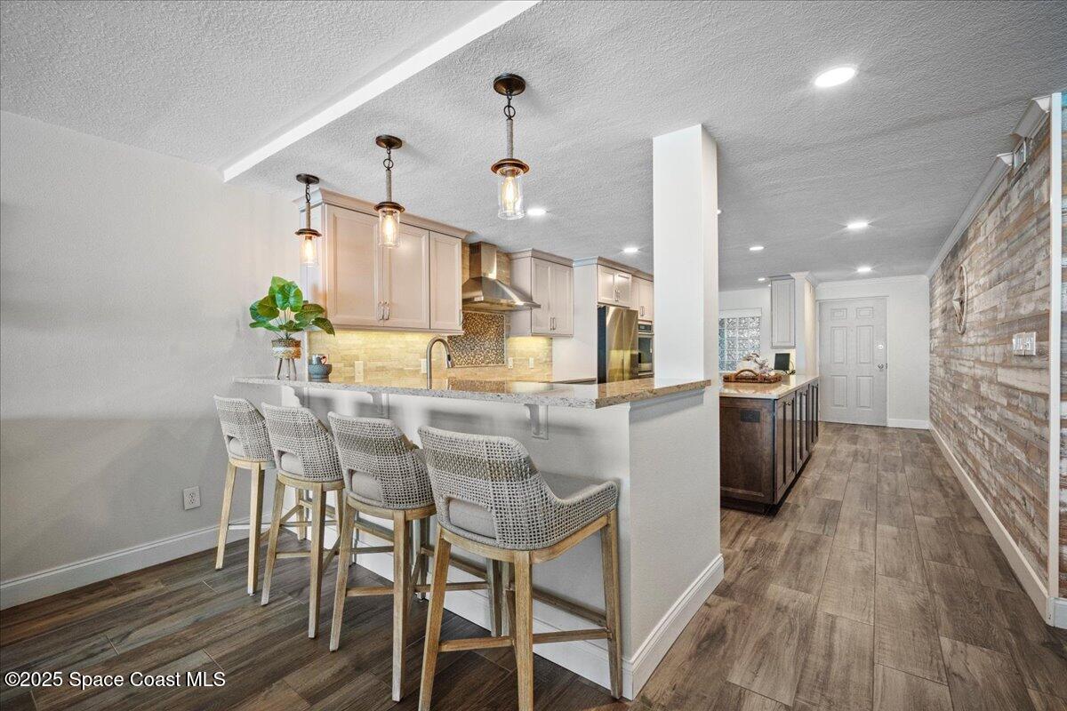 3221 South Atlantic Avenue, Unit 703 Cocoa Beach, FL 32931 - Photo 17 of 77 a kitchen with stainless steel appliances kitchen island granite countertop a table chairs and a refrigerator