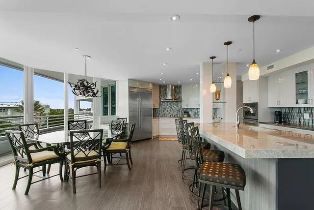 a view of a dining room with furniture wooden floor and a view of kitchen