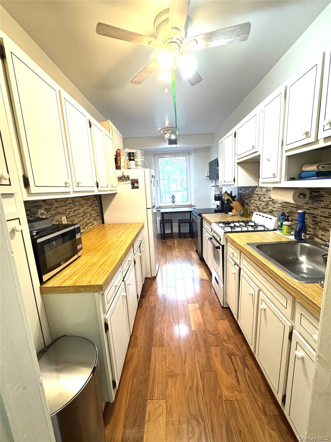 69 Harney Road, Unit 5B Scarsdale, NY 10583 - Photo 5 of 17 a kitchen with stainless steel appliances a stove a sink dishwasher a oven with white cabinets and wooden floor