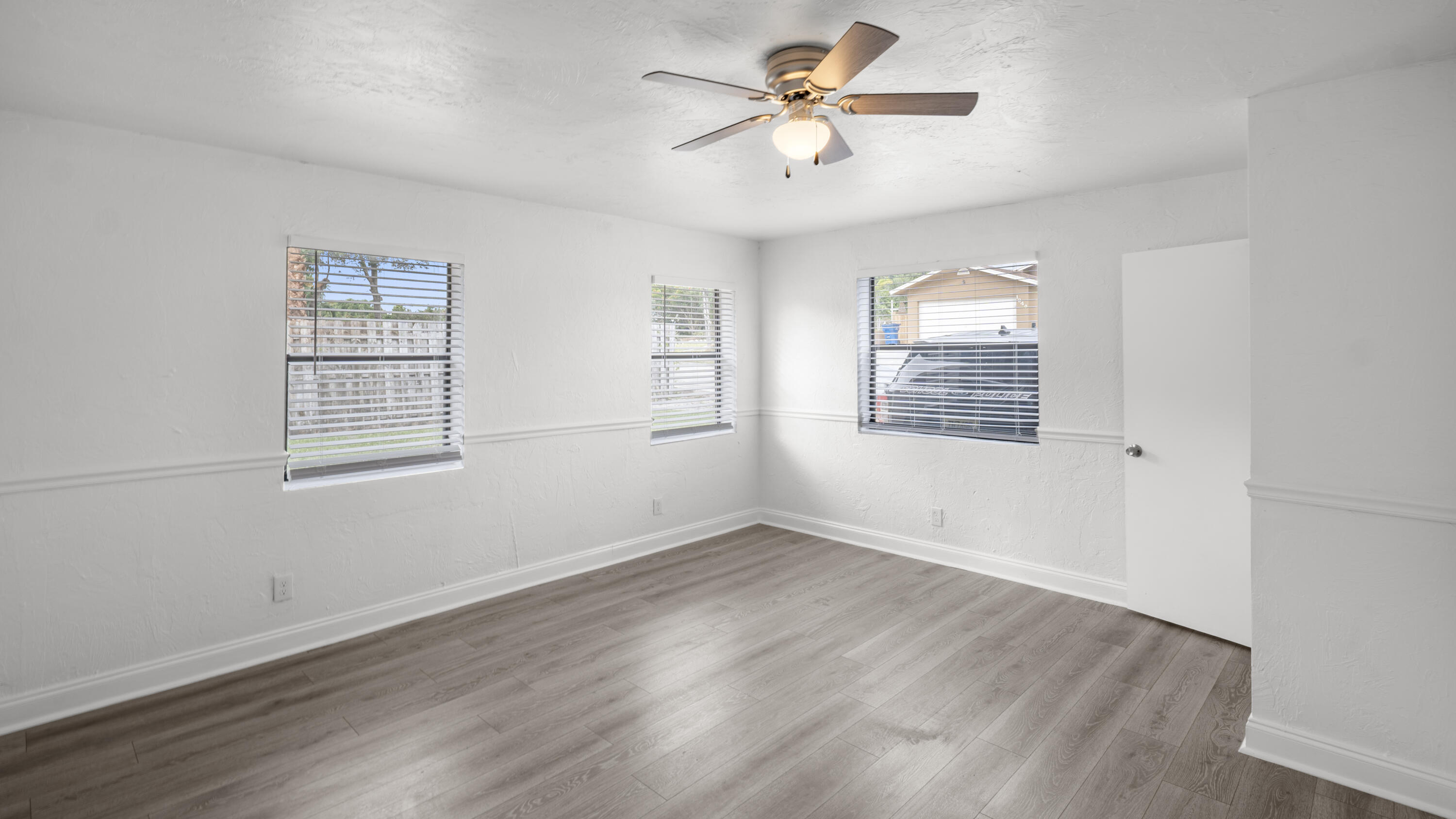 1233 West 32nd Street Riviera Beach, FL 33404 - Photo 11 of 25 a view of an empty room with a window and wooden floor