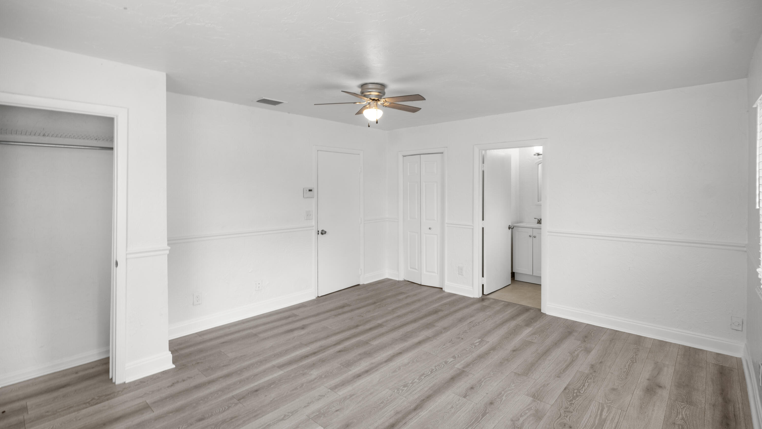 1233 West 32nd Street Riviera Beach, FL 33404 - Photo 16 of 25 an empty room with wooden floor and fan