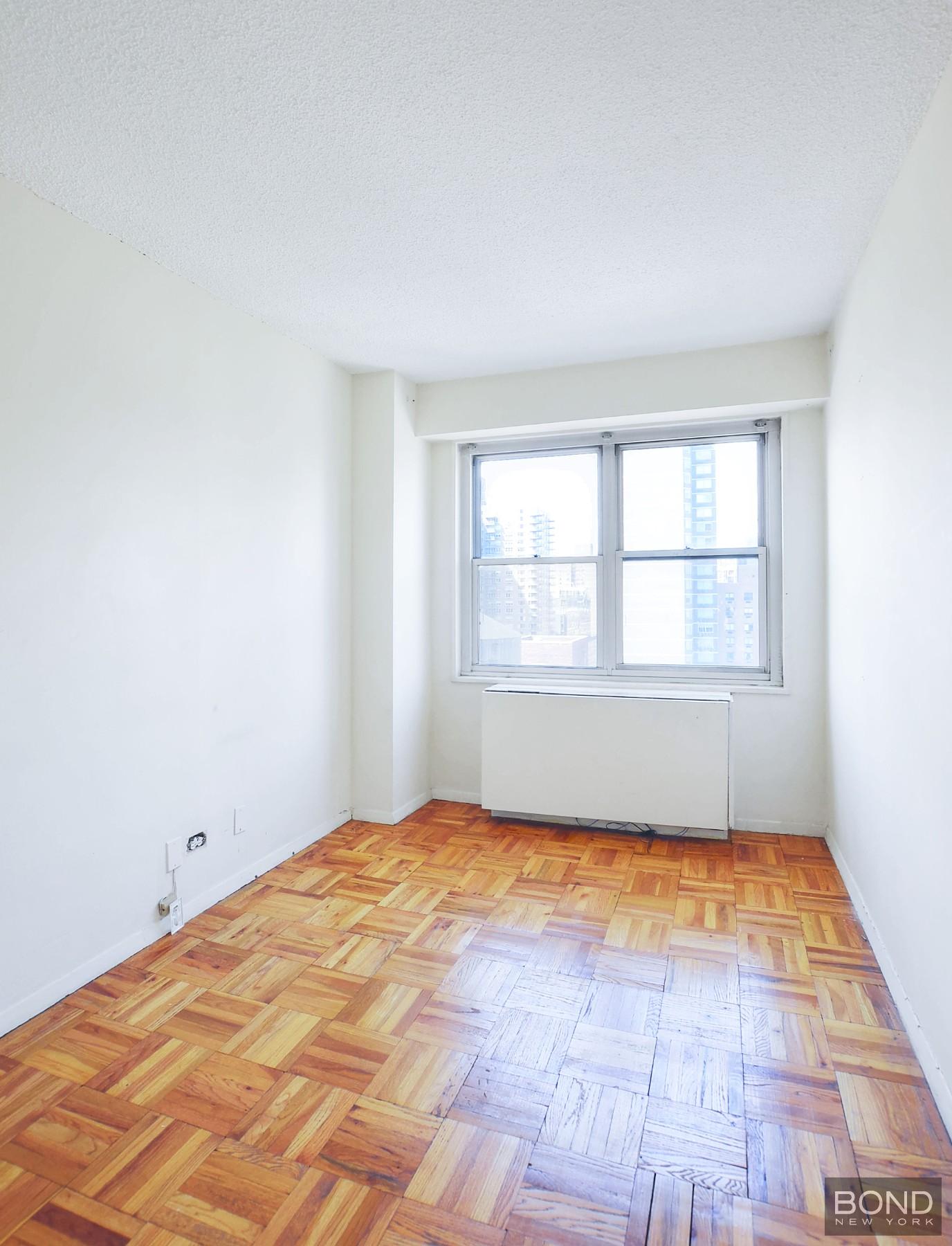 250 East 87th Street, Unit 27D Manhattan, NY 10128 - Photo 3 of 8 a view of empty room with wooden floor and fan
