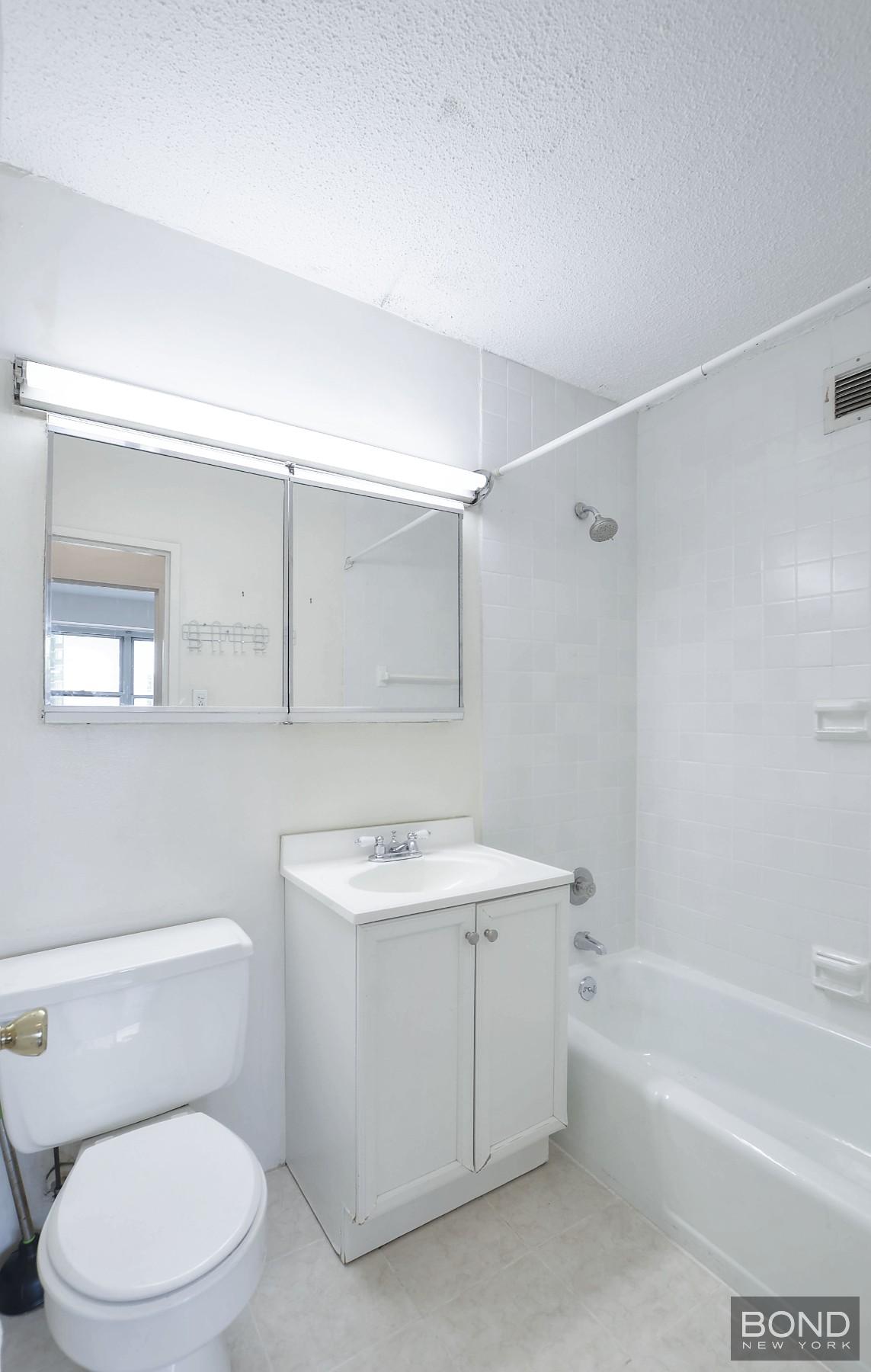 250 East 87th Street, Unit 27D Manhattan, NY 10128 - Photo 5 of 8 a bathroom with a sink a toilet and shower