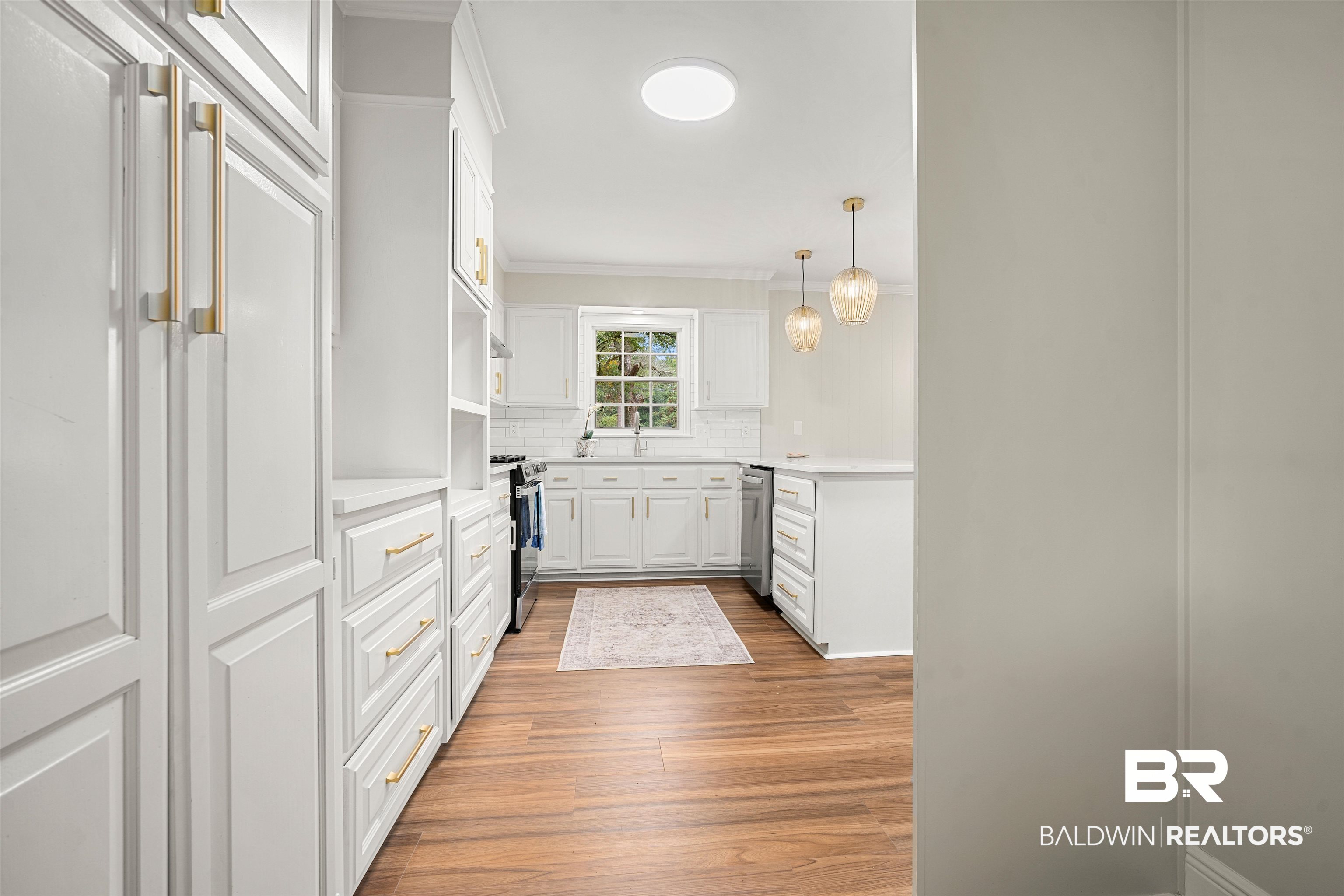 3050 Lacoste Road Mobile, AL 36618 - Photo 11 of 30 Kitchen with white cabinetry, tasteful backsplash, hanging light fixtures, crown molding, and light wood-style flooring