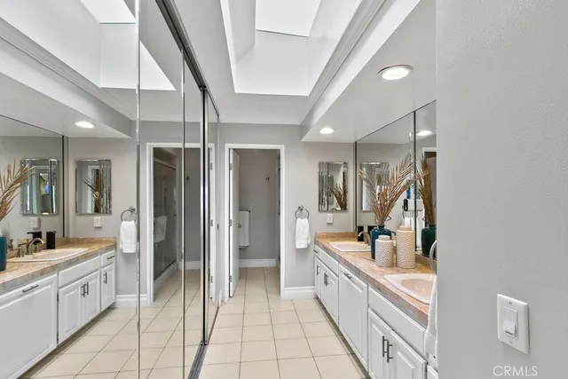 a large white bathroom with a double vanity sink and mirror