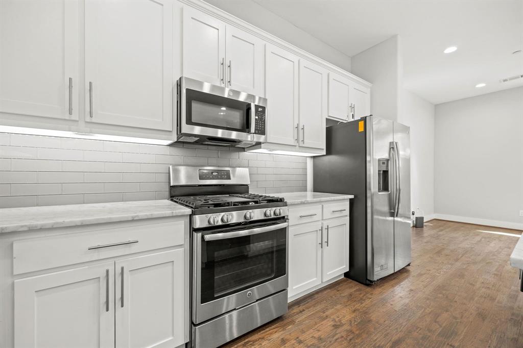 a kitchen with stainless steel appliances white cabinets a stove a microwave and a refrigerator