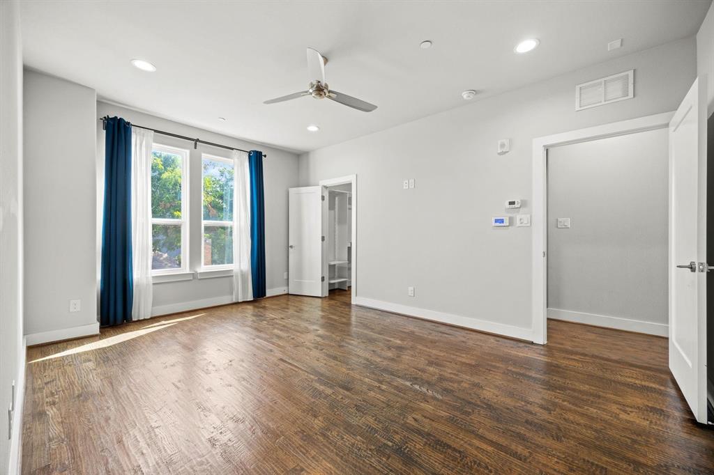 4690 Monarch Street, Unit 20 Dallas, TX 75204 - Photo 12 of 26 a view of an empty room with wooden floor ceiling fan and a window