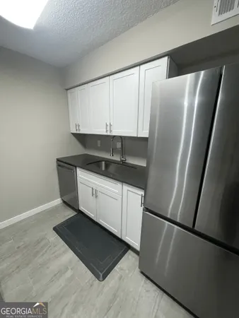 a kitchen with a refrigerator and white cabinets