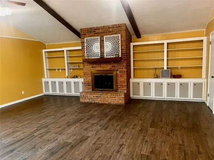 an empty room with wooden floor cabinet and windows