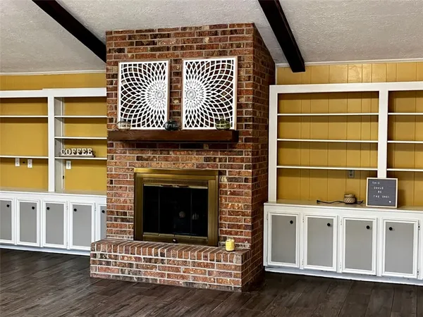 a view of an empty room with wooden floor and a fireplace