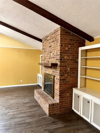 an empty room with wooden floor cabinet and windows