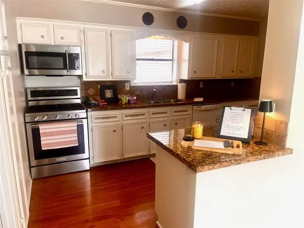 a kitchen with granite countertop wooden cabinets and a stove