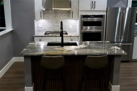 a kitchen with kitchen island granite countertop a sink cabinets and stainless steel appliances