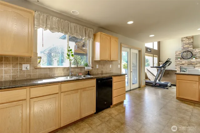 a kitchen with stainless steel appliances granite countertop a stove a sink and a granite counter tops with white cabinets next to a window
