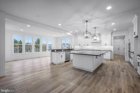 a large white kitchen with lots of counter space a sink appliances and cabinets