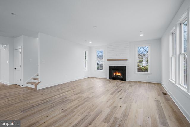 an empty room with wooden floor fireplace and windows