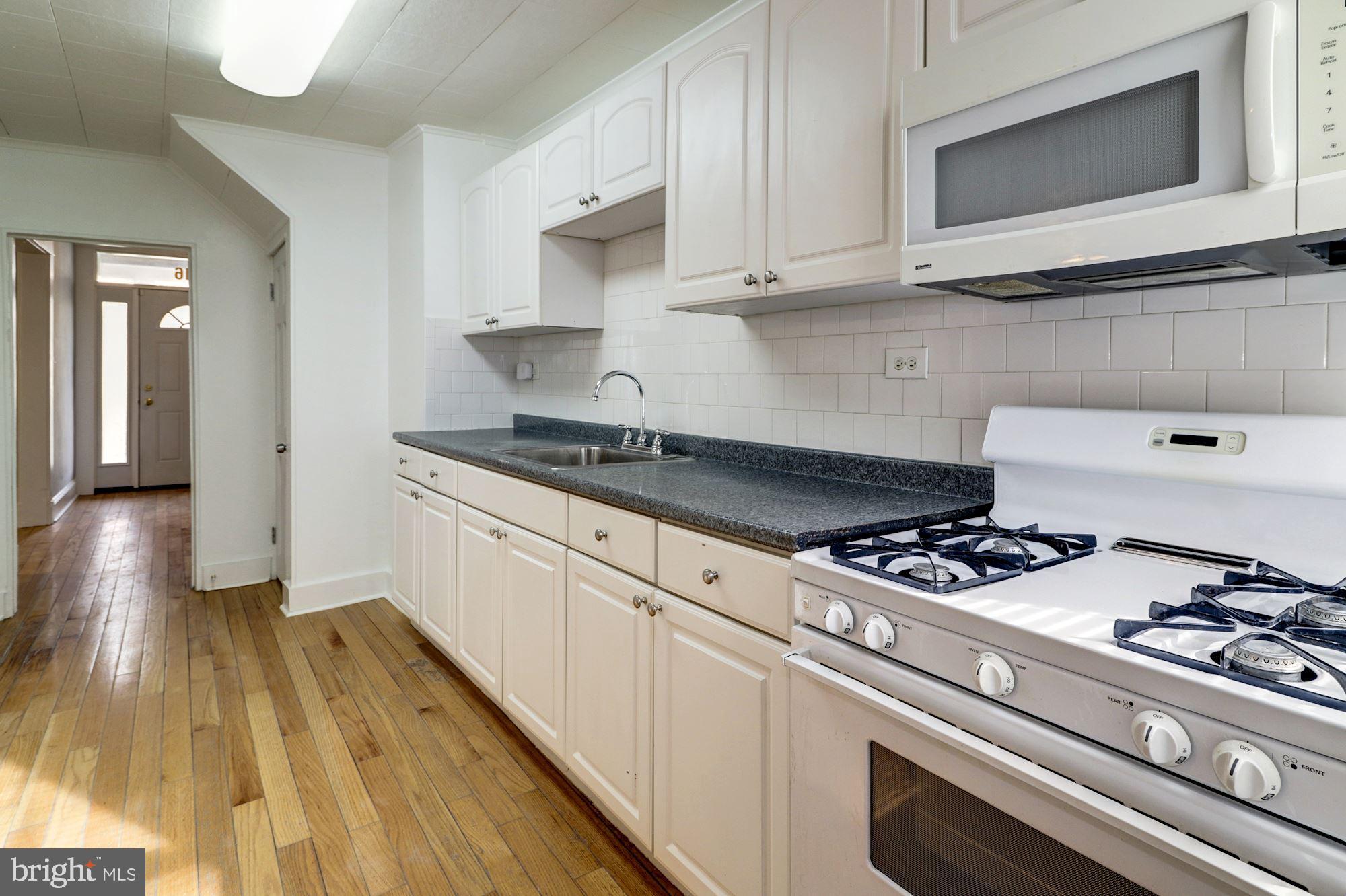 1016 North Rosedale Street Baltimore, MD 21216 - Photo 19 of 58 a kitchen with granite countertop wooden cabinets stove and sink