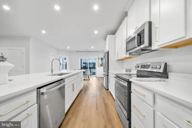 a large kitchen with stainless steel appliances lots of counter space and wooden floor