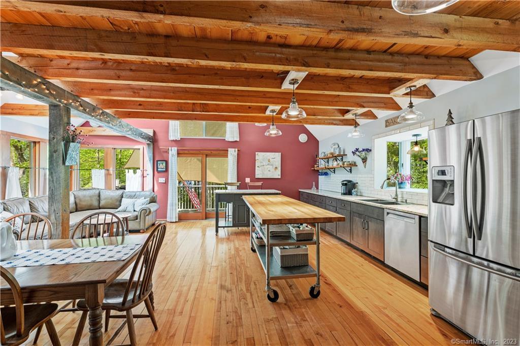 a kitchen with stainless steel appliances a dining table chairs and wooden floor